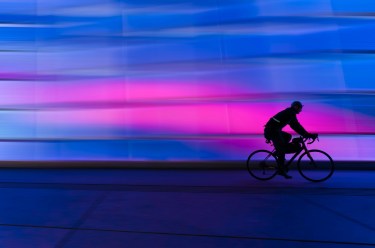 a bicyclist against a blue and pink background